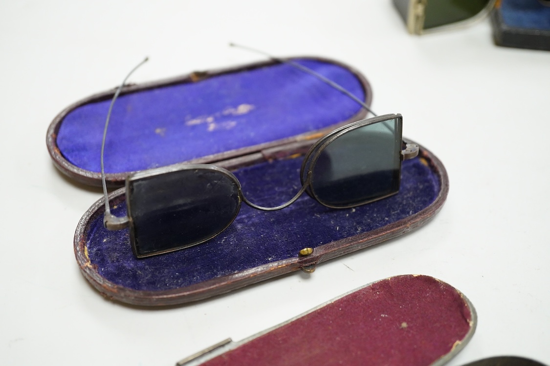 Two pairs of 19th century double D folding tinted spectacles, both cased, an unusual pair of green tinted pince nez with vulcanite side eye protectors, cased and a pair of optometrist ‘patent’ spectacles with sliding blu